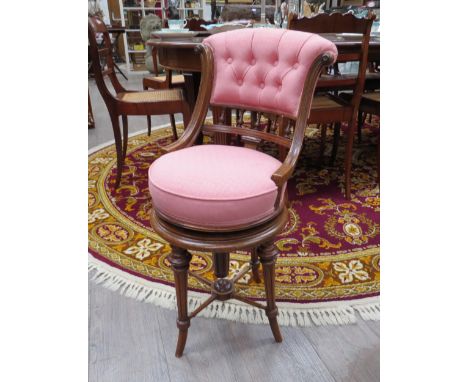 A Victorian walnut music chair with pink silk button back, swivel mechanism, reeded legs with cross stretcher, 81cm x 41cm x 