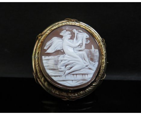A large cameo brooch depicting a female playing the harp, 6.5cmx 6cm with a vacant glass panel back 