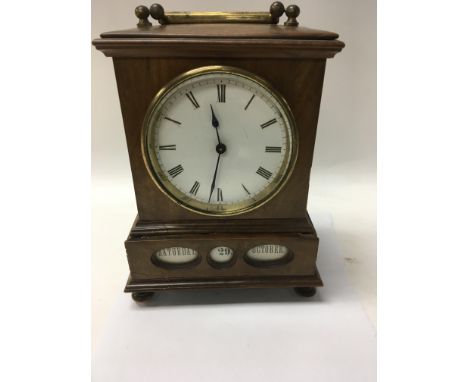 A unusual Victorian walnut mantle clock the circular dial with Roman numerals below inset with a calendar drawer.