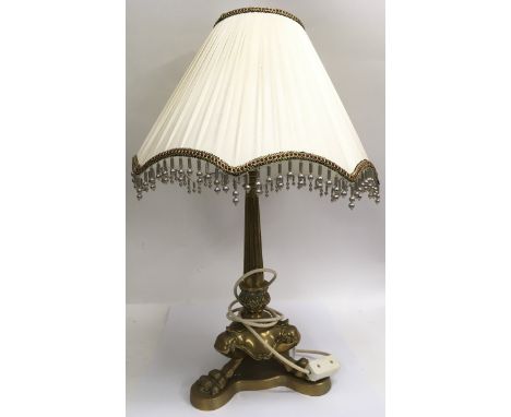 A heavy brass lamp formed as lion paw feet, with shade.Approx 43cm, excluding shade.