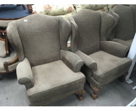 A traditional design three piece suite comprising a pair of wing arm chairs with ball and claw feet and a matching three seat
