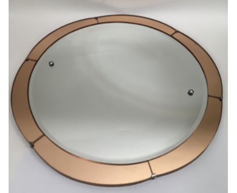 A circular Art Deco mirror with peach colour surround