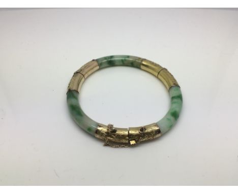 A Jadeite and yellow metal bangle, approx 21g.