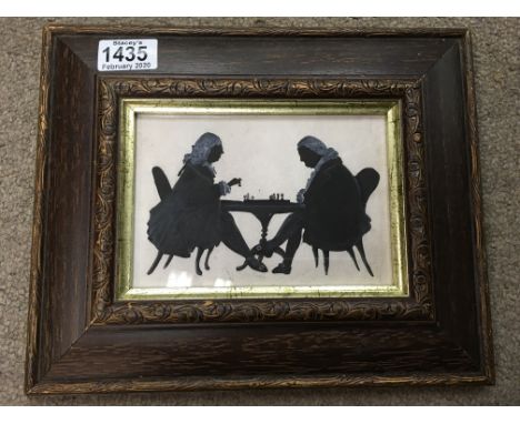 A brown framed silhouette of two Georgian style figures playing chess