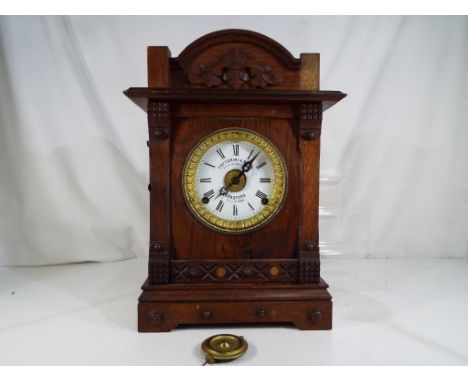 An oak cased table alarm clock by Fattorini and Sons, Bradford, marked to the white enamel dial Automatic Patent Alarm, paten