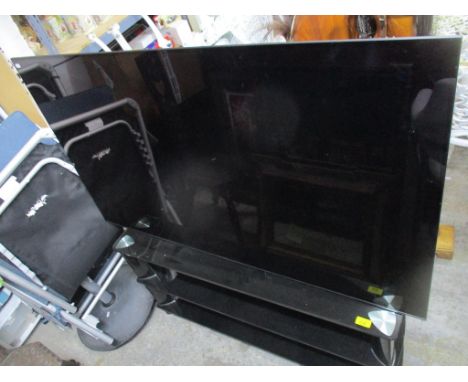 A Bravia 55.5 inch flat screen TV with speaker, on a wooden glass TV stand.Location: 