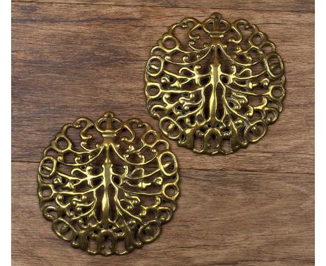 Cotswold School pair of brass terminals for a pair of fire dogs, of pierced design, 20th Century, unmarked, 16cm across (2)Pr