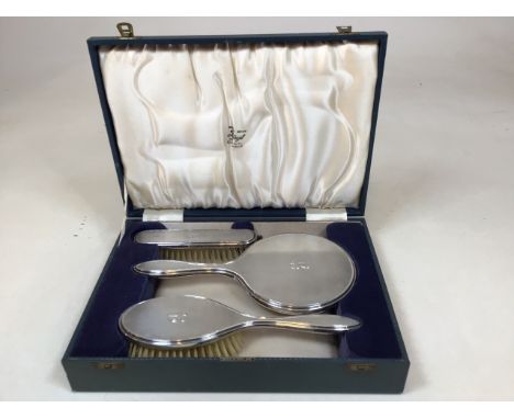 A boxed silver dressing table set with two brushes and a hand mirror. Retailed by Liangs Glasgow. Hallmarked Birmingham, 1960