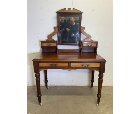 An early 20th century mahogany dressing table with large ceramic and brass castors, two large desk drawers with mirror above 