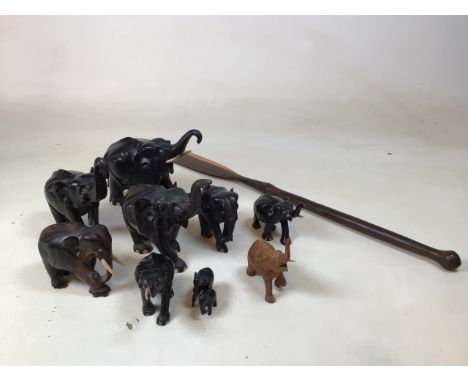A collection of ten wooden elephants, some ebony, together with a wooden spear. Length of spear 87cm. Tallest elephant 18cm t
