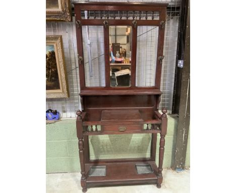 An early 20th century hall stand with six period brass hooks a bevelled central mirror, base with storage and two sections fo