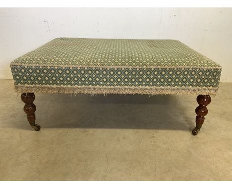 A large foot rest with turned legs and brass and ceramic castors. W:105cm x D:79cm x H:40cm