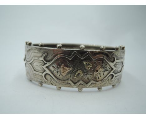 A Victorian silver hinged bangle having engraved and applique gold decoration and beaded rim, approx 24g
Condition Report&nbs