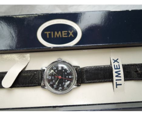 A 1970's military style wrist watch by Timex having Arabic 24hr numeral dial to black face in steel case on black leather str
