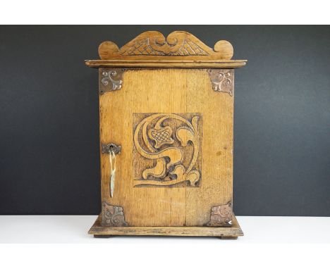 Arts and Crafts carved table top or wall hung small medicine cabinet with carved floral front panel and decorative pediment, 