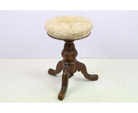 Antique mahogany music stool having a rotating seat raised on a carved column on three tripod legs. Measures 52cm tall. 
