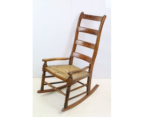 20th century ladder back, rush seated rocking chair with arms, H 97cm x W 49cm D 45cm 