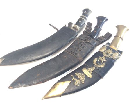 Three Early 20th Century Kukri Knifes The Traditional Nepalese knife. With horn handles one with a brass handle the leather s