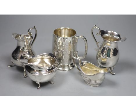 A Victorian engraved silver footed Christening mug, Edward Hutton, London, 1886 and four silver cream jugs, various, 12.3 oz 