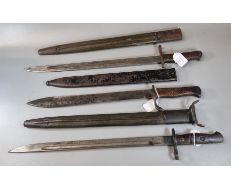 Two Remington US bayonets with scabbards together with another, probably German with wooden grip and metal scabbard.  (3)  (B