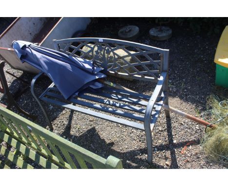 A metal ornate two seater garden bench and a garden parasol