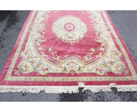 A Washed Chinese Carpet; the carpet having a pink ground with beige floral border, approx 250 x 350 cms.