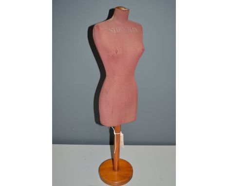 An early 20th Century counter top female mannequin, by Stockman, upholstered in red material raised on turned wooden base, 68
