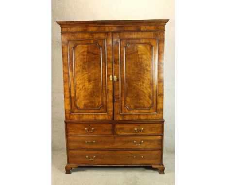 A 19th century mahogany linen press, the twin panel doors opening to reveal hanging rail and brushing slides raised above two