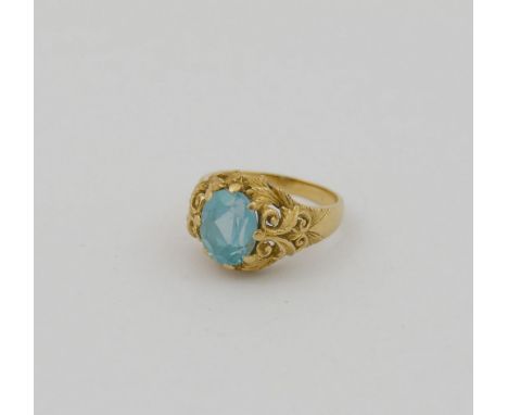 An ornate yellow metal ring, set with single oval mixed-cut synthetic spinel, the shank stamped '750, finger size K 1/2, 4.9g