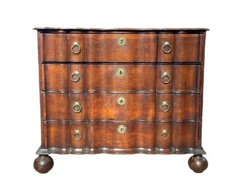 A Dutch oak double serpentine commode. 18th century, fitted four long drawers with brass ring handles, on bun feet, height 77