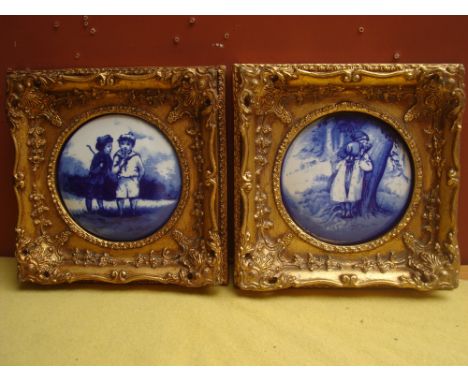 A pair of Doulton style blue and white transfer decorated circular plaques depicting playing children, mounted in gilt frames