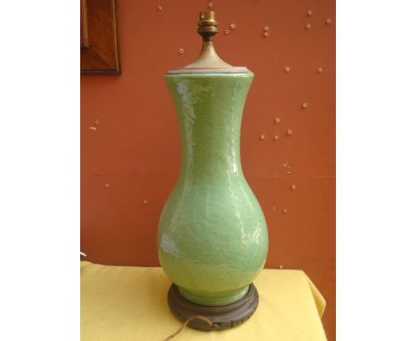 A Chinese pale green ground baluster form vase fitted as a table lamp on pierced and carved hardwood stand.
51cm high. 