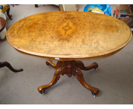 A Victorian burr walnut and marquetry inlaid oval loo table with tilt action on carved pedestal and four outswept scroll legs