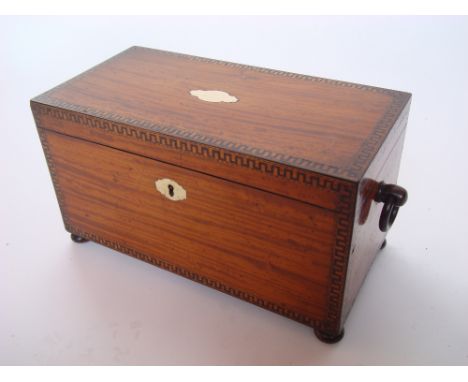 A George III satinwood tea caddy, of rectangular form, inlaid with dentil banded and barbers pole strung borders.  With ring 