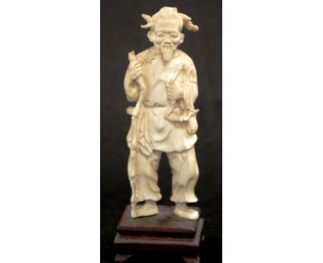 Early carved ivory sage holding a stick figure on a carved timber stand, C1920, height 14.5cm approxNB.This item cannot be ex