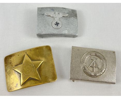 3 Military metal belt buckles. An East German silver tone buckle with hammer and compass detail, a modern copy of German WWII