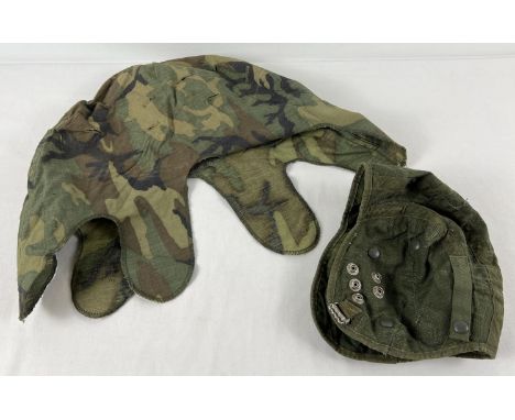 A vintage green camo helmet cover together with a green aviation helmet liner with military issue arrow mark. 
