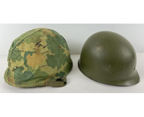 A US Vietnam era M1 steel helmet with bullet damage, complete with camo cover, Firestone liner and chinstrap. Wearer's name o