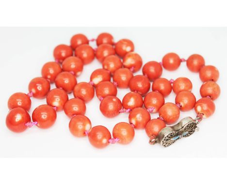 A single strand of coral beads with enamel and filigree clasp marked Silver, beads diam. approx. 9mm each, length 46cm.&nbsp;