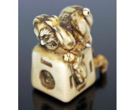 A Japanese carved ivory netsuke formed as an oni catcher on top of a box with protruding limbs, height 37mm.  Condition - bot