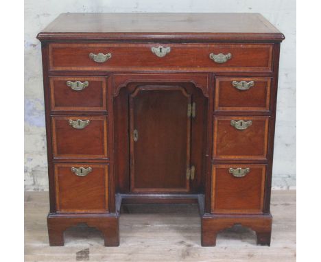 A George III mahogany knee hole desk, cross-banded top with moulded edge above one long and six small oak lined drawers with 