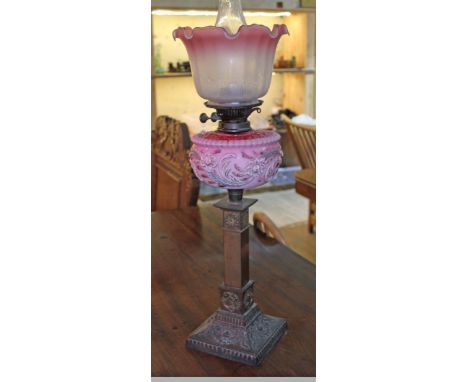 A Victorian brass column oil lamp with pink pressed glass reservoir and etched glass shade, total height (with flue) 69cm.The