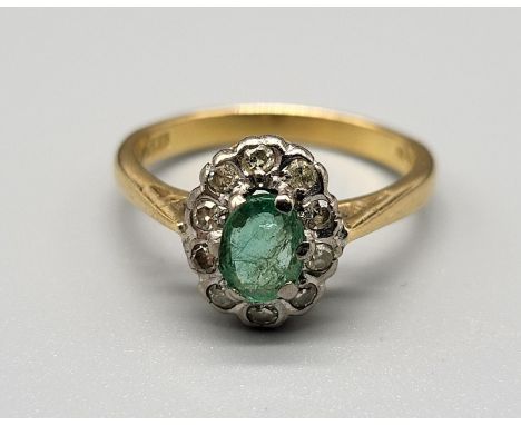 An 18 K yellow gold ring with an oval emerald surrounded by a halo of diamonds. Ring size: M, weight: 3.8 g. 