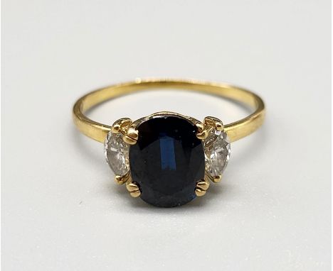 An 18 K yellow gold ring with an oval cut dark blue sapphire, flanked by two marquise cut sapphires. Ring size: M, weight: 2.