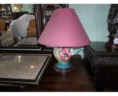 A Moorcroft Anemone pattern table lamp, having tube-lined decoration on a green ground, mounted to circular wooden base, 35cm