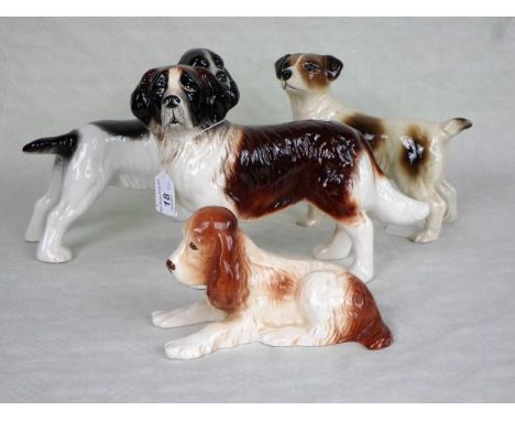 A Sylvac model of a recumbent spaniel numbered 114, 16cm wide, together with three further ceramic dog figurines.