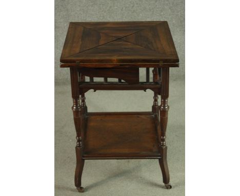 An Edwardian walnut envelope card table, the square top opening to reveal a green baize interior, on turned legs joined by an