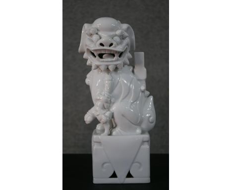 A 20th century blanc de chine Chinese ceramic foo dog on pierced square base. H.35 W.12 D.10cm 