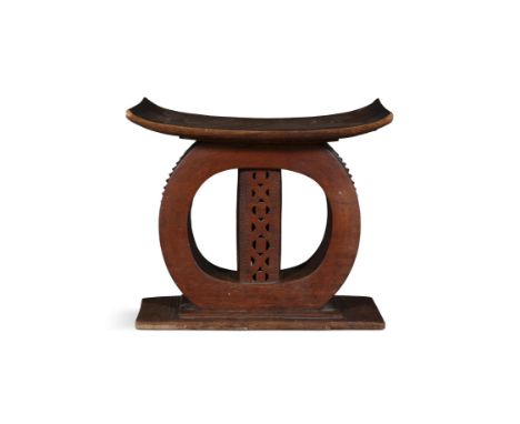 AN AFRICAN HARDWOOD STOOL, Ashanti, Ghana, with bowed seat supported on a lattice work centre column and rounded arches, on a