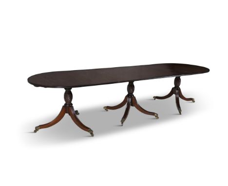 A REGENCY STYLE MAHOGANY TRIPLE PILLAR EXTENDING DINING TABLEof oval form, the solid panel top with reeded edge , supported o